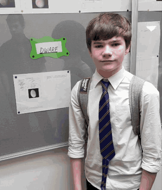 a boy stands in front of a sign that says dwarf