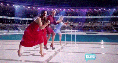 three women in red dresses are running on a track with a bravo logo behind them