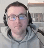 a man wearing glasses and headphones is sitting in front of a microphone .