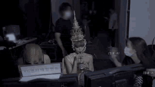 a woman wearing a crown is sitting in front of a computer screen