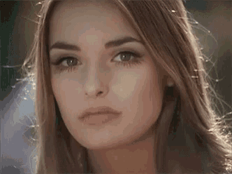 a close up of a woman 's face with long blonde hair looking at the camera .