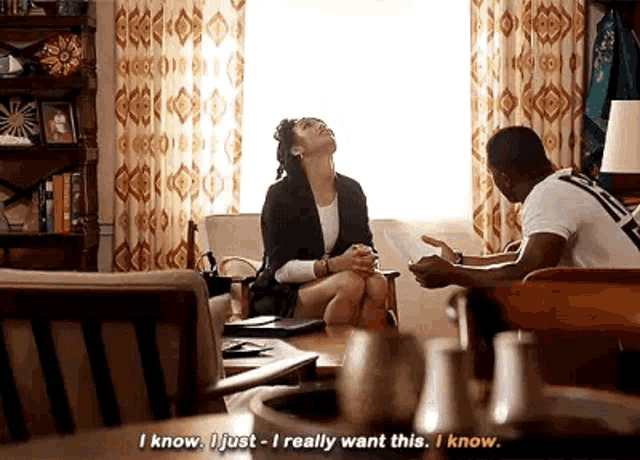 a man and a woman are sitting on a couch in a living room talking .