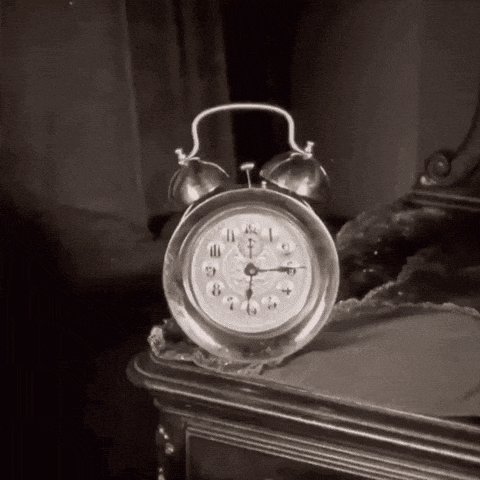 a black and white photo of an alarm clock on a nightstand which shows the time as 4:20