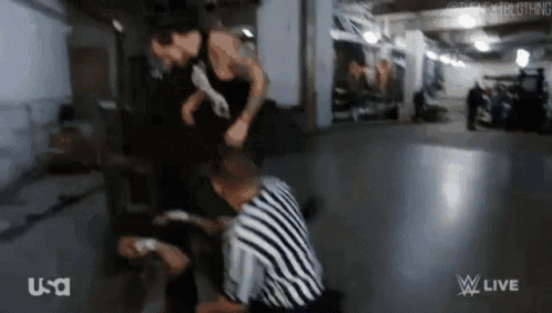 a referee is kneeling down next to a man in a striped shirt .