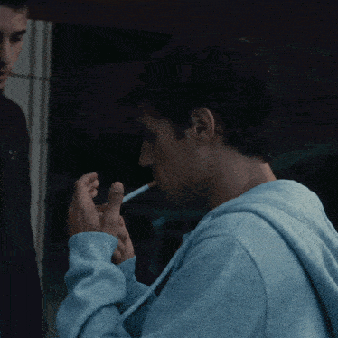 a man smoking a cigarette with a puma logo on his sleeve