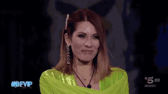 a woman in a green sequined top is on a television screen with the hashtag #gfvip on it