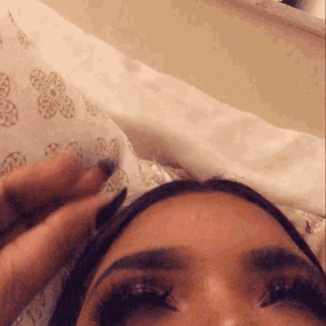 a close up of a woman 's face while laying on a bed with a pillow .