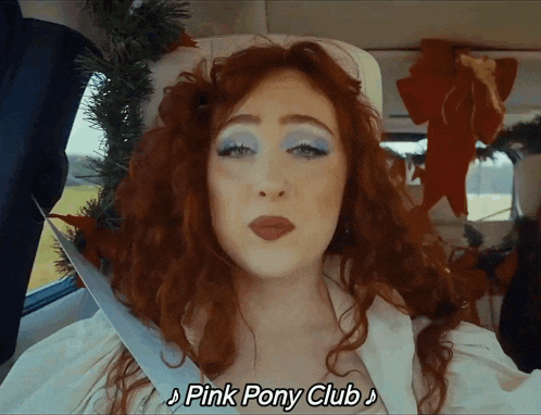 a woman in a car with pink pony club written on the bottom of her face