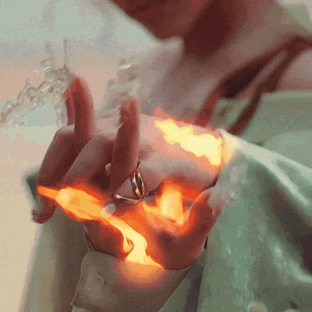 a woman with a ring on her finger is holding a fireball