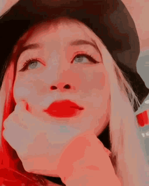 a close up of a woman 's face with red lipstick and a black hat .