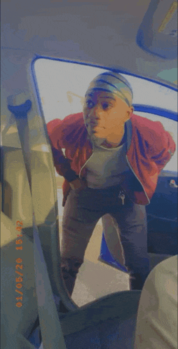 a man in a red jacket is standing in a car with a knife in his hand .