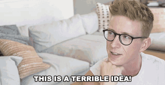 a man with glasses is sitting on a couch with the words this is a terrible idea below him