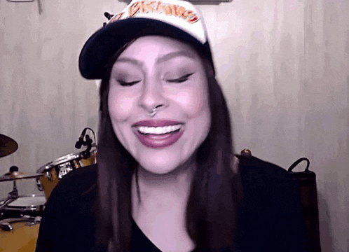 a woman wearing a hat that says thrasher on it smiles