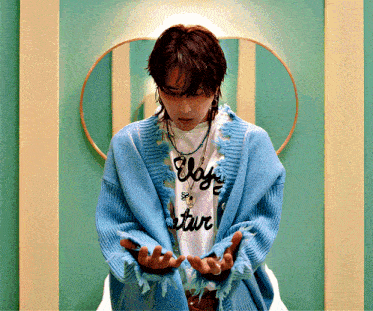 a man wearing a blue cardigan and a t-shirt that says " vogue star "