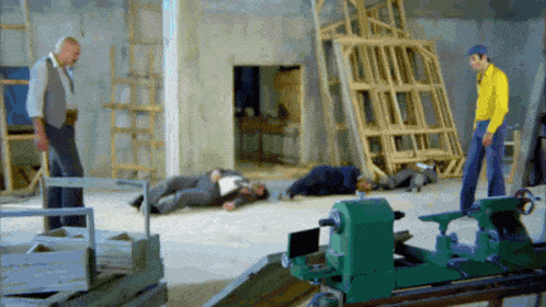 a man in a yellow shirt is standing next to a lathe