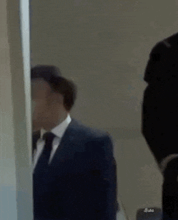 a man in a suit and tie is standing in front of a mirror .