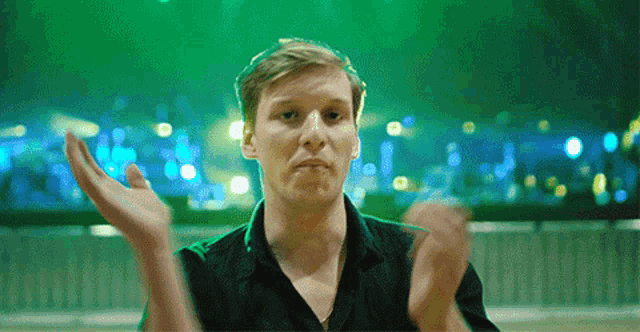 a man in a black shirt is clapping his hands in the air