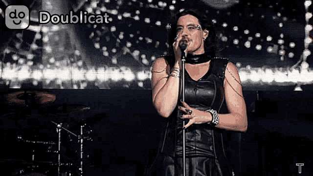 a woman singing into a microphone with doublecat written on the bottom right