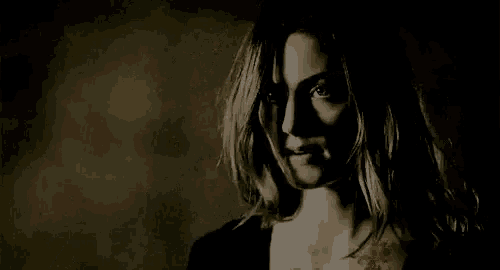 a close up of a woman 's face in a dark room with her mouth open .