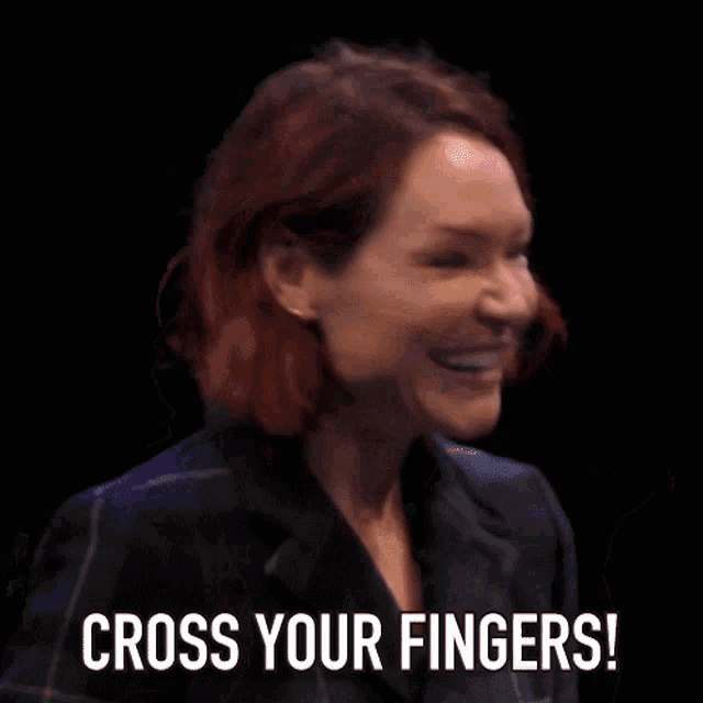 a woman with red hair is making a gesture with her fingers and says cross your fingers
