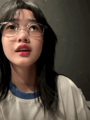 a young woman wearing glasses and a white shirt is looking up .