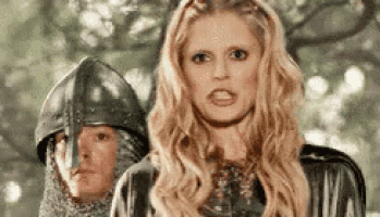 a woman in a black dress is standing next to a man in a helmet .