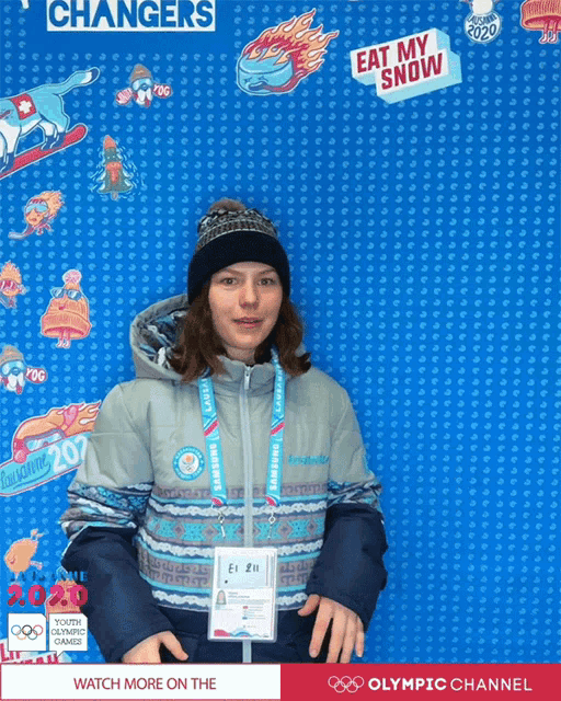 a woman stands in front of a wall that says ' eat my snow '