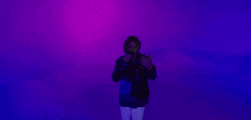 a man is singing into a microphone with a purple background .