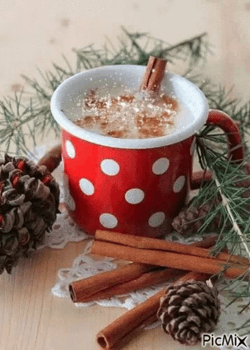 a red and white polka dot cup of hot chocolate with cinnamon sticks and pine cones .