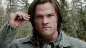 a man with long hair is scratching his head .