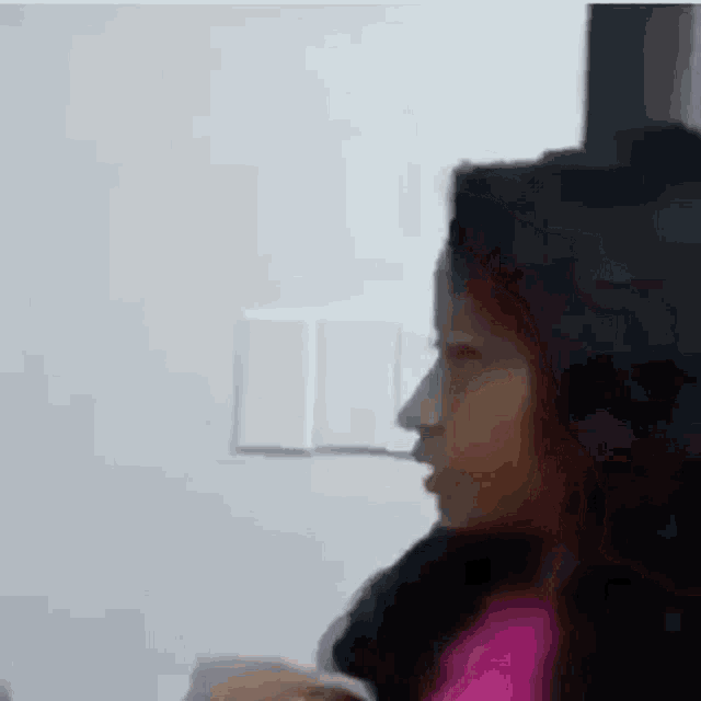 a woman is sitting in front of a white wall .