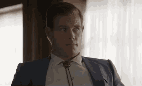 a man in a suit and tie is sitting in a room .