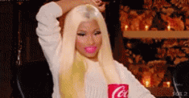 a woman with blonde hair is holding a red cup of coca cola .