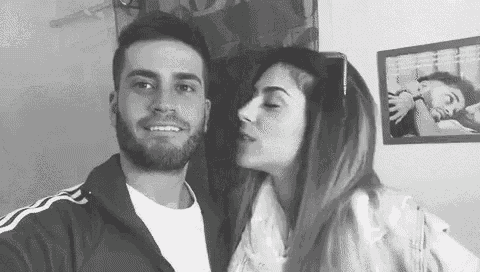 a black and white photo of a man and a woman kissing .