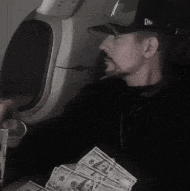 a man wearing a new york yankees hat holds a stack of money