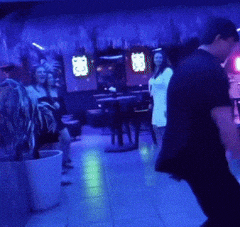 a group of people are standing in a dark room with blue lights and a sign that says ' a ' on it