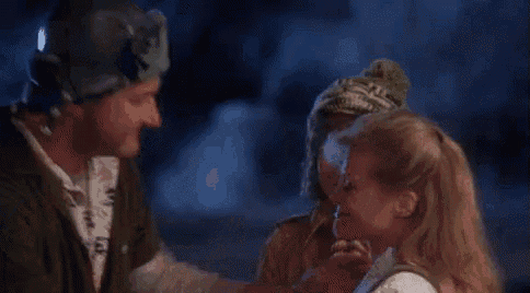 a man in a helmet is kissing a woman on the cheek while a boy looks on .