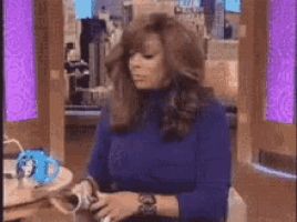 a woman in a blue sweater is sitting at a table with a cup of coffee .