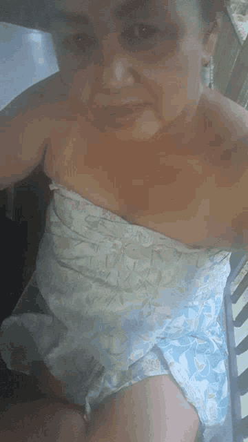 a woman is taking a selfie while wearing a strapless blue and white dress