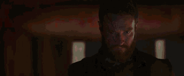 a man is standing in a dark room with a red light coming out of his head .