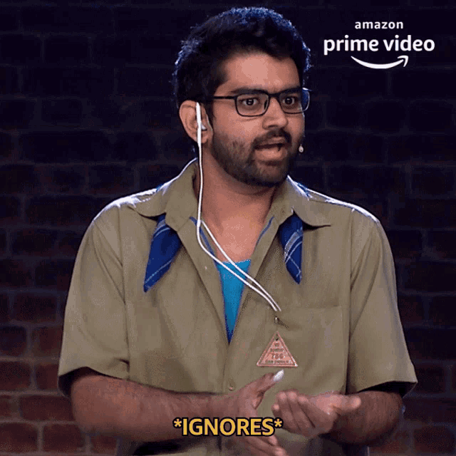 a man wearing ear buds says " ignores " in front of an amazon prime video sign