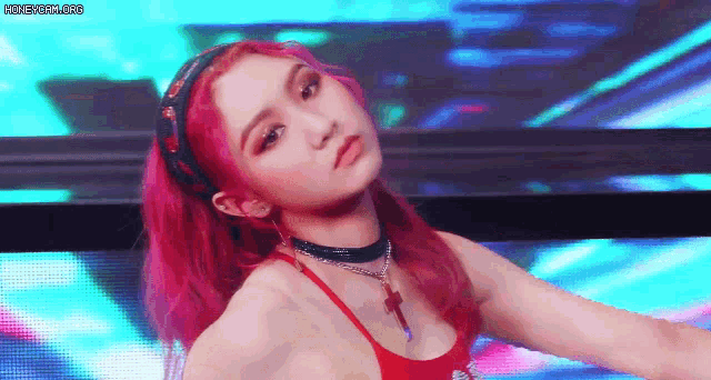 a woman with red hair is dancing on a stage in front of a colorful background .