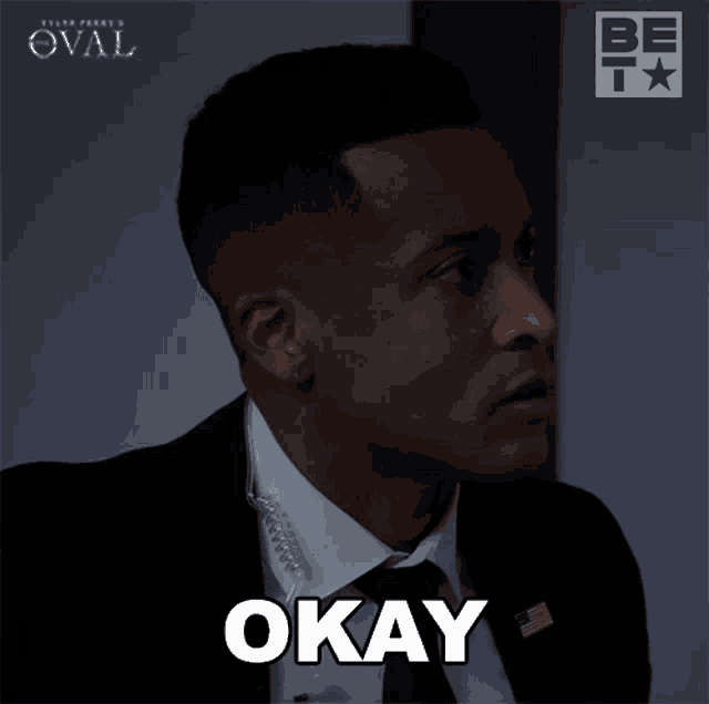 a man in a suit and tie with the word okay on his face