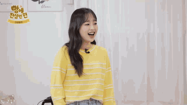 a woman in a yellow striped sweater is dancing in a room with korean writing on the wall