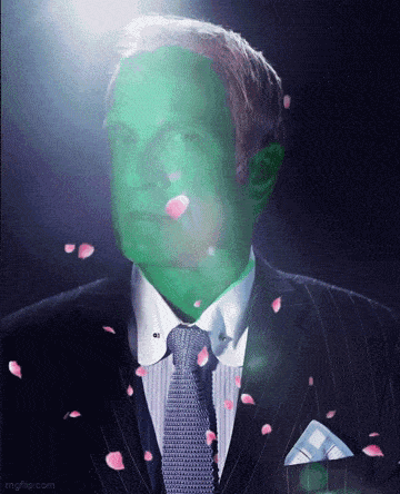 a man in a suit has a green face and petals falling around him