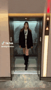 a woman in a black jacket is standing in an elevator with tiktok written on the bottom right corner