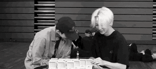 a black and white photo of two men sitting next to each other in a room .