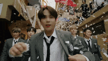a group of men in suits and ties are standing in front of a crowd .