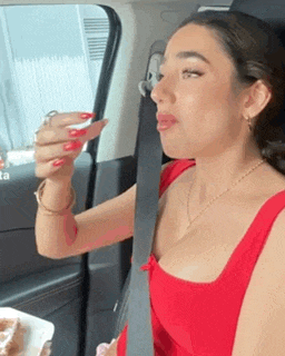a woman in a red dress is sitting in a car with a plate of food .