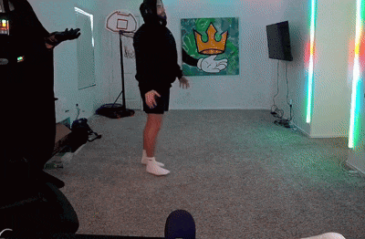 a man is standing in a living room with a basketball hoop and a painting of a crown on the wall